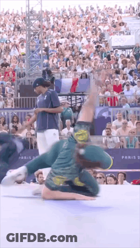 A Man Is Doing A Trick In Front Of A Crowd With A Sign That Says Paris 2 GIF