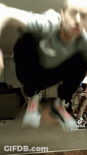 A Man Is Doing A Trick In Front Of A Mirror While Wearing Nike Shoes . GIF
