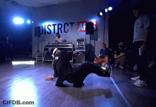 A Man Is Doing A Trick In Front Of A Sign That Says District Afs GIF