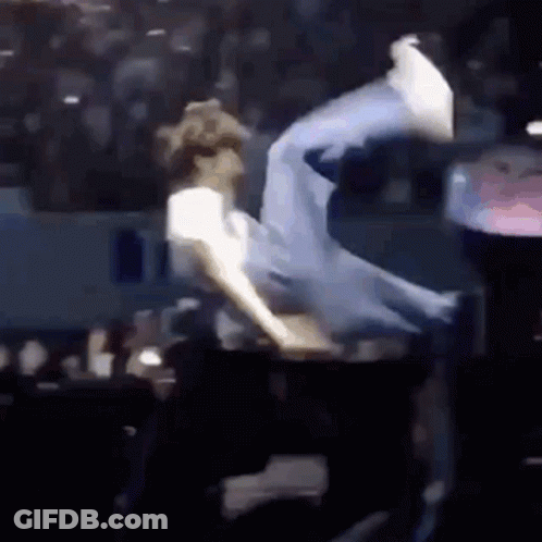 A Man Is Doing A Trick On A Stage In Front Of A Crowd Of People . GIF