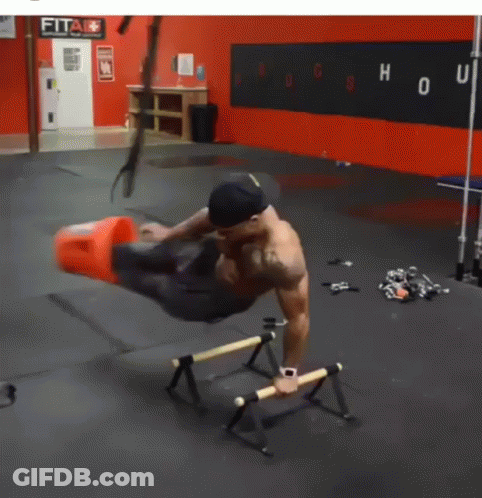 A Man Is Doing Exercises In A Gym With A Sign That Says Fit GIF
