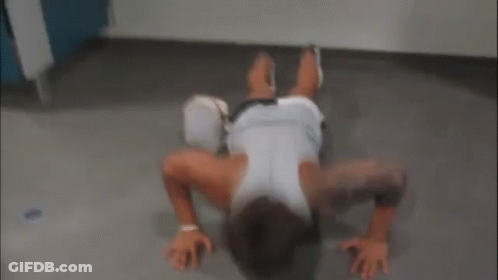 A Man Is Doing Push Ups On The Floor With A Purse On The Floor . GIF
