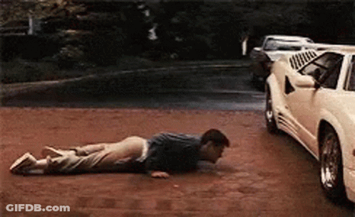 A Man Is Doing Push Ups On The Ground In Front Of A White Car GIF