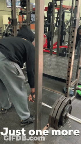 A Man Is Doing Squats In A Gym With The Words Just One More Behind Him GIF