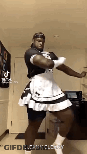 A Man Is Dressed As A Maid And Dancing In A Kitchen . GIF