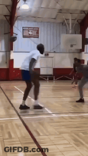 A Man Is Dribbling A Basketball On A Court GIF
