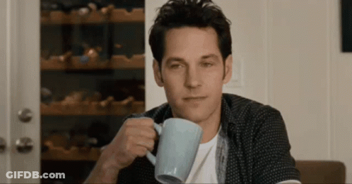 A Man Is Drinking A Cup Of Coffee And Looking At The Camera GIF