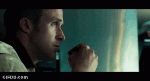 A Man Is Drinking A Cup Of Coffee And Looking Out The Window GIF