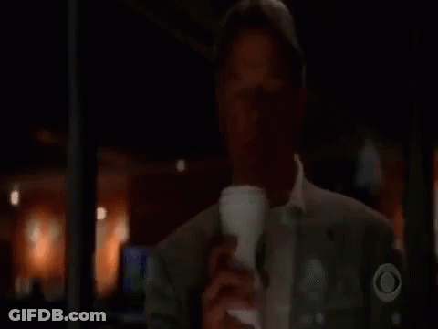 A Man Is Drinking A Cup Of Coffee From A Cup In A Dark Room . GIF