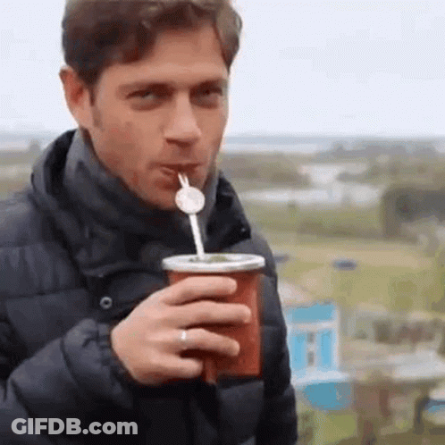 A Man Is Drinking A Drink With A Straw Through A Cup . GIF