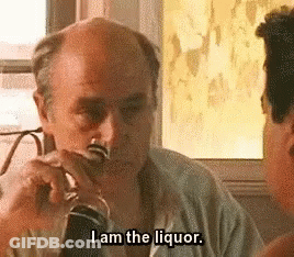A Man Is Drinking A Glass Of Liquor And Talking To Another Man . GIF