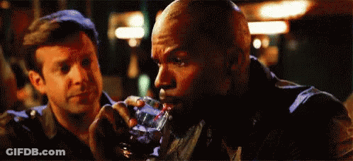 A Man Is Drinking A Glass Of Whiskey While Another Man Looks On . GIF