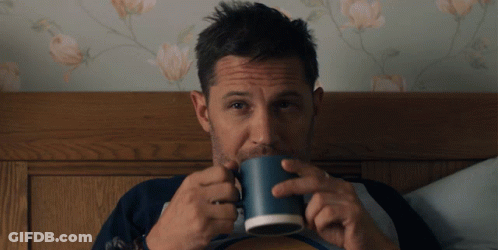 A Man Is Drinking From A Blue Mug In Bed GIF
