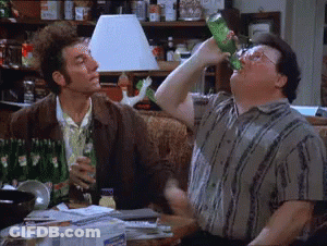 A Man Is Drinking From A Green Bottle While Another Man Looks On . GIF