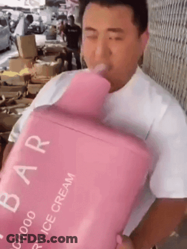 A Man Is Drinking From A Pink Container That Says Strawberry Ice Cream On It GIF