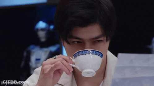 A Man Is Drinking From A White Cup With A Blue And White Design On It . GIF