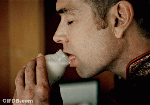 A Man Is Drinking Milk From A Bottle With A Label That Says ' A ' On It GIF
