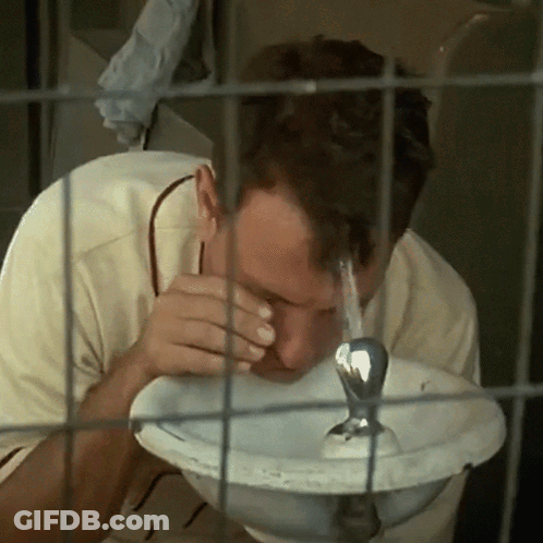 Man Drinking Water From Fountain In Cage GIF