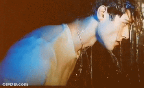 A Man Is Drinking Water From A Fountain With A Blue Light Behind Him GIF