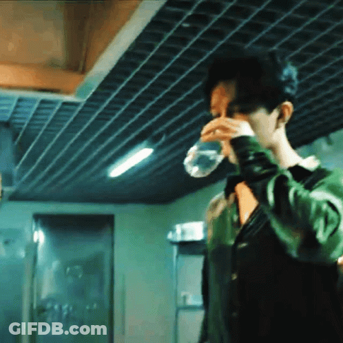 A Man Is Drinking Water From A Plastic Bottle . GIF