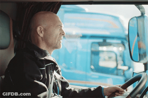 A Man Is Driving A Blue Truck And Looking Out Of The Window GIF