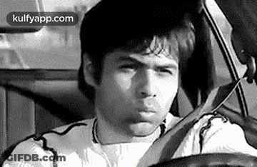 A Man Is Driving A Car And Making A Funny Face In A Black And White Photo . GIF