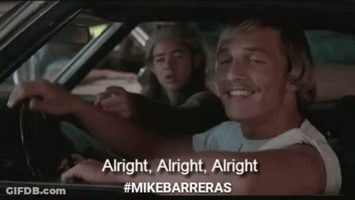 A Man Is Driving A Car And Pointing At The Camera While Another Man Sits Behind Him . GIF