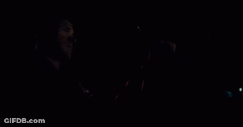 A Man Is Driving A Car At Night And Holding The Steering Wheel In His Hand . GIF