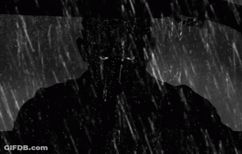 A Man Is Driving A Car In The Rain And Looking Out The Window . GIF