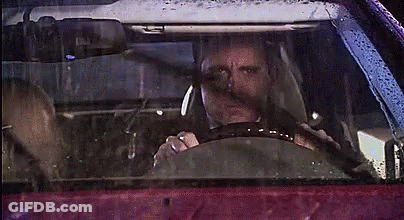 A Man Is Driving A Car In The Rain With A Woman Sitting In The Back Seat . GIF