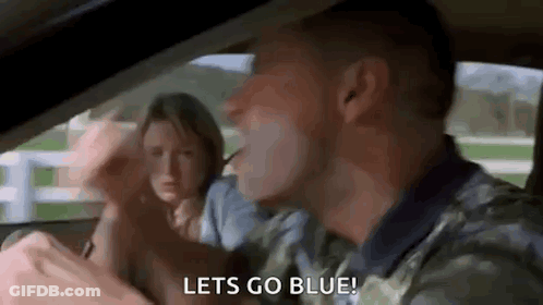 A Man Is Driving A Car With A Woman Behind Him And Says `` Let 'S Go Blue '' . GIF