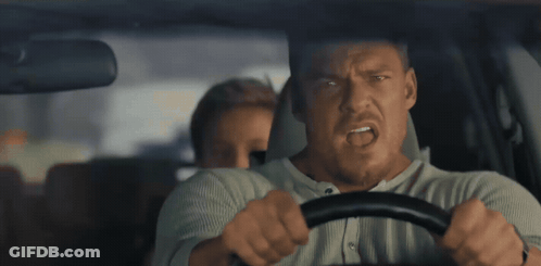A Man Is Driving A Car With Another Man Behind Him GIF