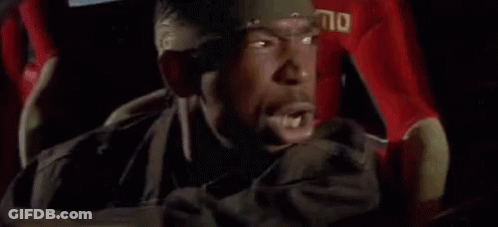 A Man Is Driving A Car With Blood On The Steering Wheel And A Bandana On His Head . GIF