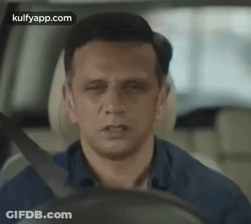 A Man Is Driving A Car With His Eyes Closed And His Mouth Open . GIF