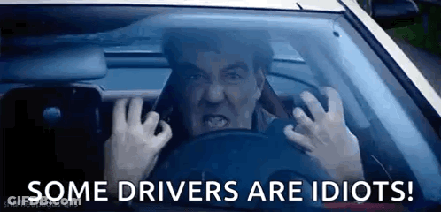 A Man Is Driving A Car With His Hands On The Steering Wheel And The Words `` Some Drivers Are Idiots '' Below Him . GIF