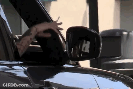 A Man Is Driving A Car With His Hands Out The Window . GIF