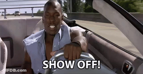 A Man Is Driving A Car With The Words Show Off On The Steering Wheel GIF