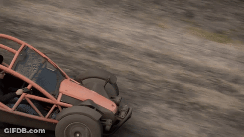 A Man Is Driving A Red And Black Buggy On A Dirt Road GIF