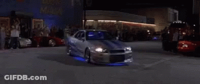 A Man Is Driving A Sports Car At Night In A Garage . GIF