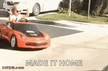 A Man Is Driving A Toy Car On A Street . GIF