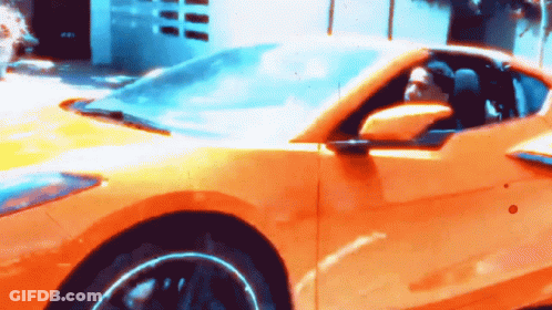 A Man Is Driving A Yellow Sports Car With A Blue Sky In The Background GIF