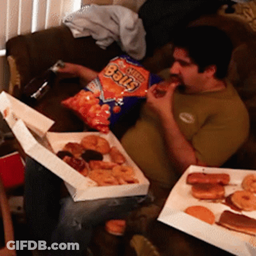 A Man Is Eating A Bag Of Cheetos Balls While Sitting On A Couch GIF
