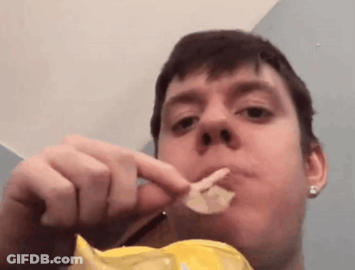 A Man Is Eating A Bag Of Potato Chips With His Mouth Open . GIF