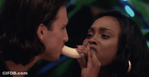 A Man Is Eating A Banana While A Woman Holds A Banana To His Mouth GIF