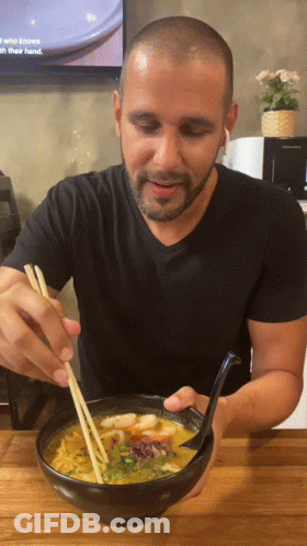 A Man Is Eating A Bowl Of Soup With Chopsticks GIF
