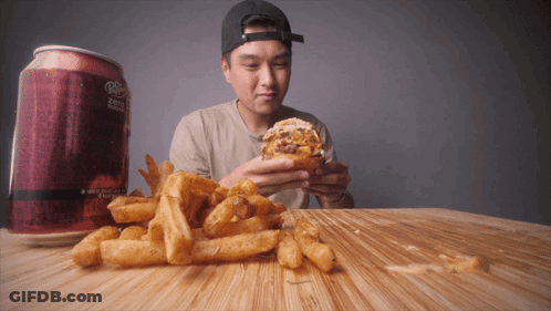 A Man Is Eating A Hamburger Next To A Can Of Diet Dr Pepper GIF