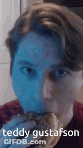 A Man Is Eating A Hamburger With The Name Teddy Gustafsson Written On The Bottom GIF