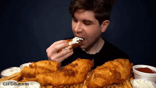 A Man Is Eating A Piece Of Fried Chicken With Ranch Dressing GIF