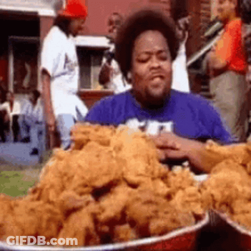 A Man Is Eating A Pile Of Fried Chicken . GIF