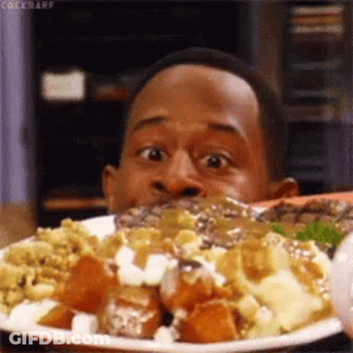A Man Is Eating A Plate Of Food And Making A Funny Face . GIF